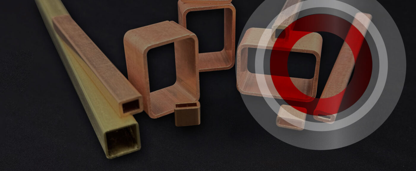 Team member at Wieland Small Tube Products standing in front of the red Wieland logo wall, representing the company’s commitment to excellence.